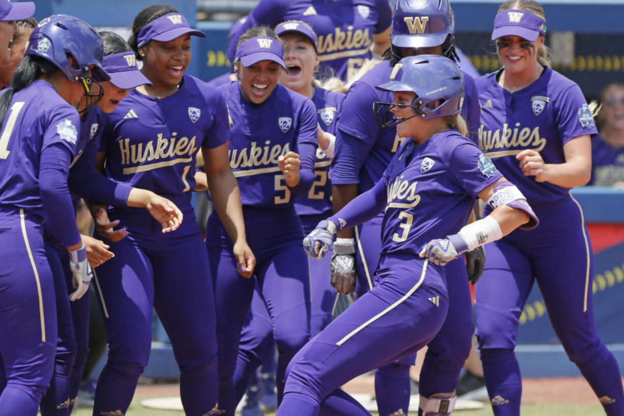 Washington celebrates a home run by Rylee Holtorf (3) at home plate during the second inning of an NCAA softball Women's College World Series game against Utah Friday, June 2, 2023, in Oklahoma City.