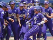 Washington celebrates a home run by Rylee Holtorf (3) at home plate during the second inning of an NCAA softball Women's College World Series game against Utah Friday, June 2, 2023, in Oklahoma City.