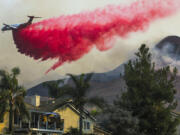 An air tanker makes a fire retardant drop behind homes on Oct. 27, 2020, in Chino Hills, California.