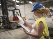 Pregnant woman working and forklift in bakcground