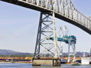 Tugs keep the ship Zhen Hua creeping slowly up the Columbia River in the center of the channel so the container crane on board will clear the Lewis and Clark Bridge on April 28, 2006, in Longview. The bridge will close for repairs Sunday.