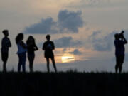 People watch as the sun sets behind clouds on Sunday, May 22, 2022, in Coral Springs. A patch of Saharan dust arrived late Friday and overnight Saturday, which may cause hazy conditions and hue-altered sunrises and sunsets.