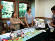 Grace DeMeo, left, and Carolyn Rice, with Clark Conservation District, talk to members of the public about the District's Poop Smart program, which offers financial assistance for people hoping to replace or repair failing septic systems and educates the public on the benefits of keeping animal feces out of the watershed, during a lake water-quality open house held Wednesday, July 12, 2023, at Lacamas Lake Lodge in Camas.