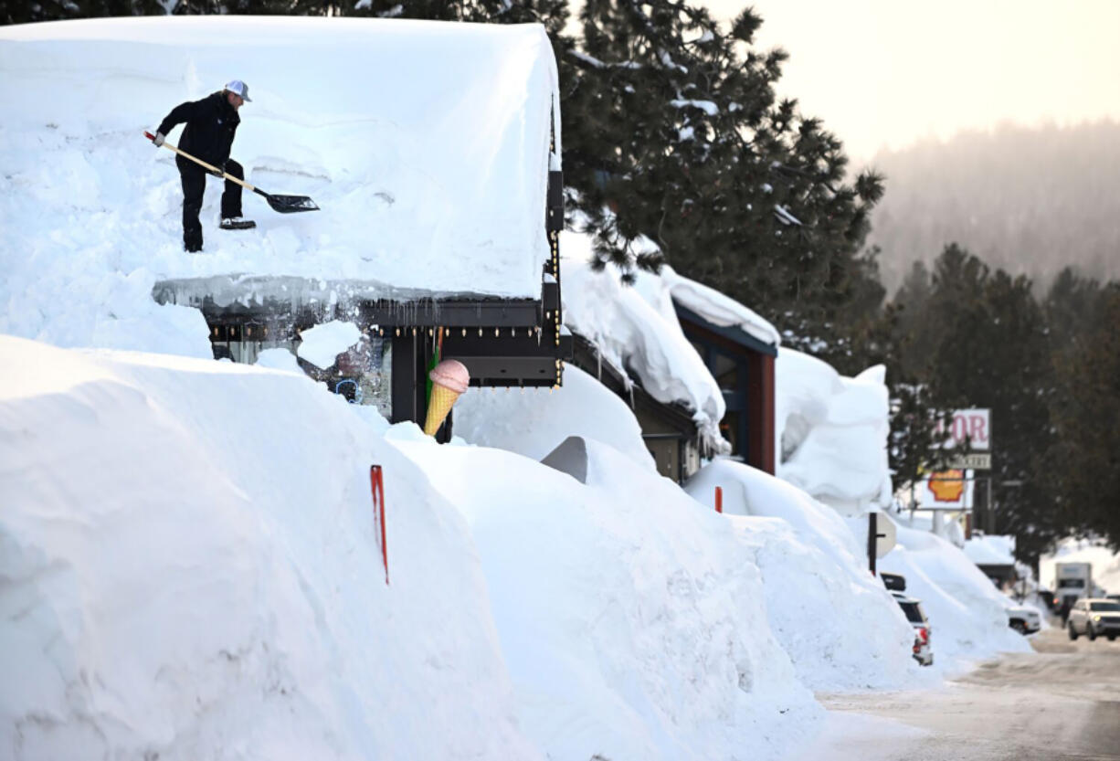 Owner Brang Miller shovels snow off the roof of Mammoth Fun Shop as locals try to dig out in between storms last winter in Mammoth Mountain, Calif.
