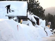 Owner Brang Miller shovels snow off the roof of Mammoth Fun Shop as locals try to dig out in between storms last winter in Mammoth Mountain, Calif.