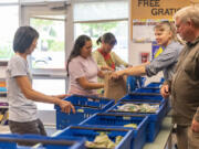 Farm to Heart cofounders Phyllis Chun, left, April Thatcher, second from right, and Brad Thatcher organize baskets of fresh produce at a recent pickup at Fruit Valley Elementary School in Vancouver.