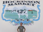 Hockinson Market owner Jim VanNatta stands in front of a mural on the store's north side. The cow is a nod to the building's 1928 origins with the Hockinson Dairy Co-Op Association.