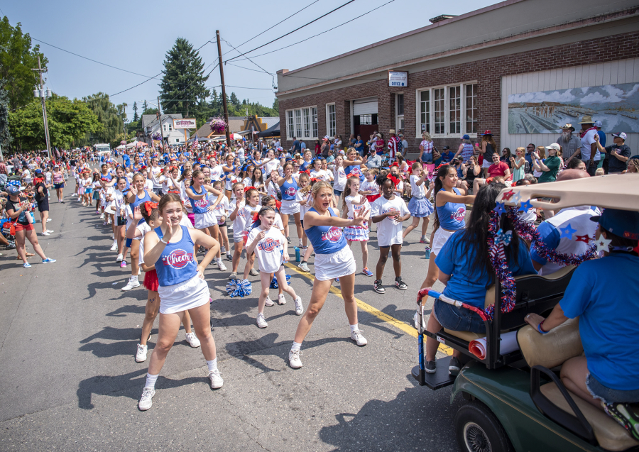 Ridgefield High School cheerleaders, in blue, lead other cheerleaders in a dance during Ridgefield's annual Fourth of July parade in 2023.