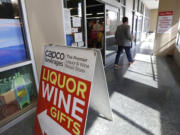 In this photo taken Wednesday, March 25, 2020, a shopper leaves a liquor store in Seattle.