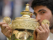 Spain's Carlos Alcaraz celebrates with the trophy after beating Serbia's Novak Djokovic to win the final of the men's singles on day fourteen of the Wimbledon tennis championships in London, Sunday, July 16, 2023.