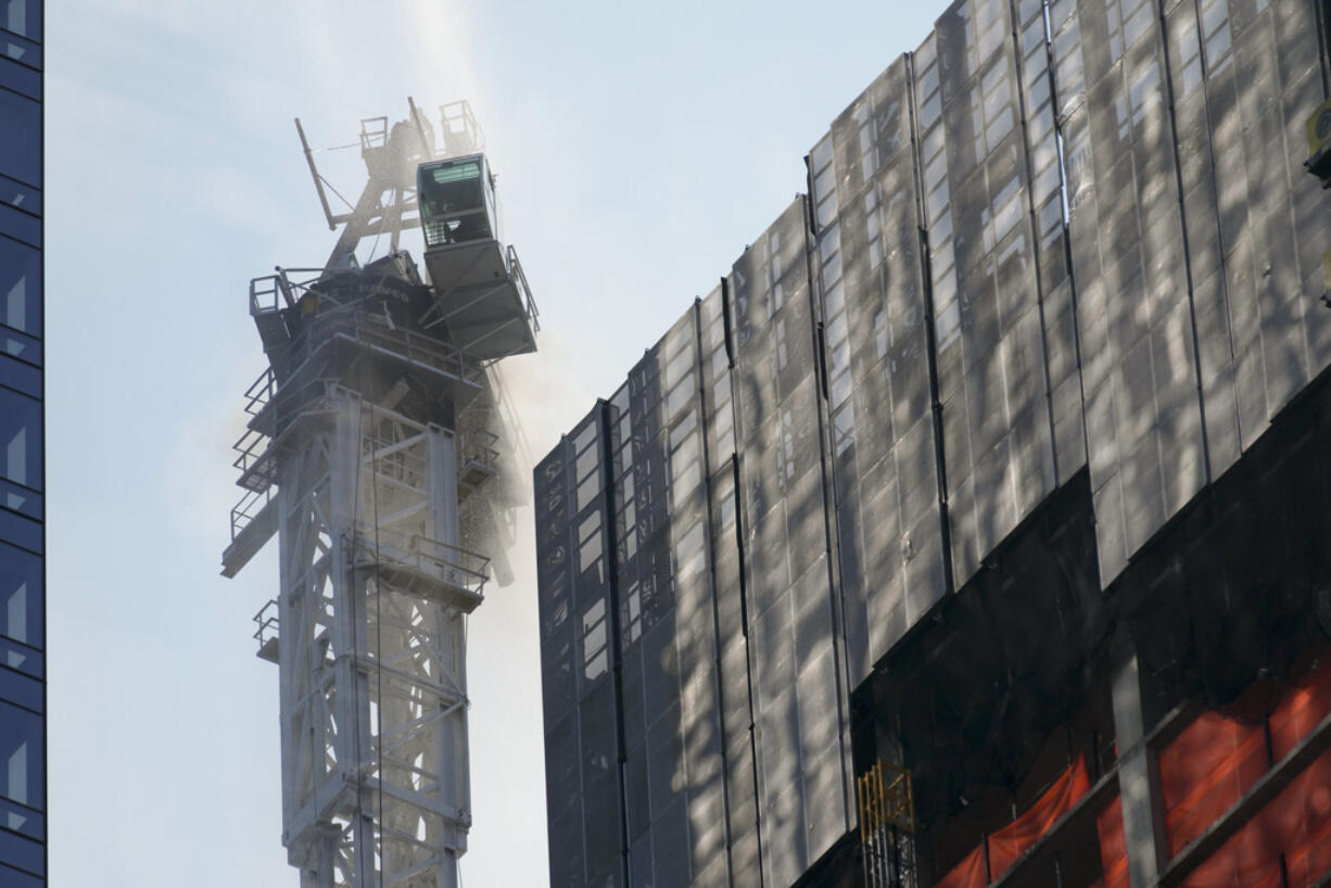 Smoke rises from a construction crane that caught fire in Manhattan, Wednesday, July 26, 2023, in New York.  The crane lost its long arm, which smashed against a nearby building, dangled and then plummeted to the street as people ran for their lives on the sidewalk below.