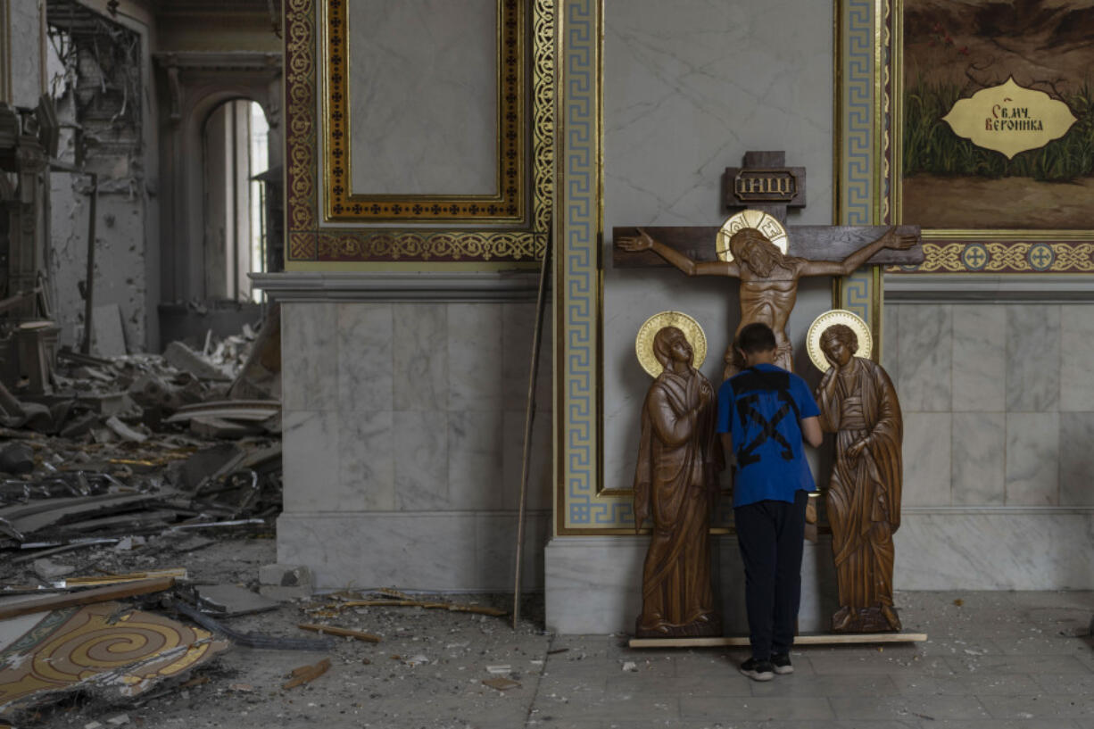 A boy kisses the statue of Jesus while helping clean up inside the Odesa Transfiguration Cathedral after the church was heavily damaged in Russian missile attacks in Odesa, Ukraine, Sunday, July 23, 2023. In just a week, Russia has fired more than 125 missiles and drones at the Odesa region, but none struck quite as deeply as the one that destroyed the cathedral, which stands at the center of the city's romantic, notorious past and its deep roots in both Ukrainian and Russian culture. (AP Photo/Jae C.