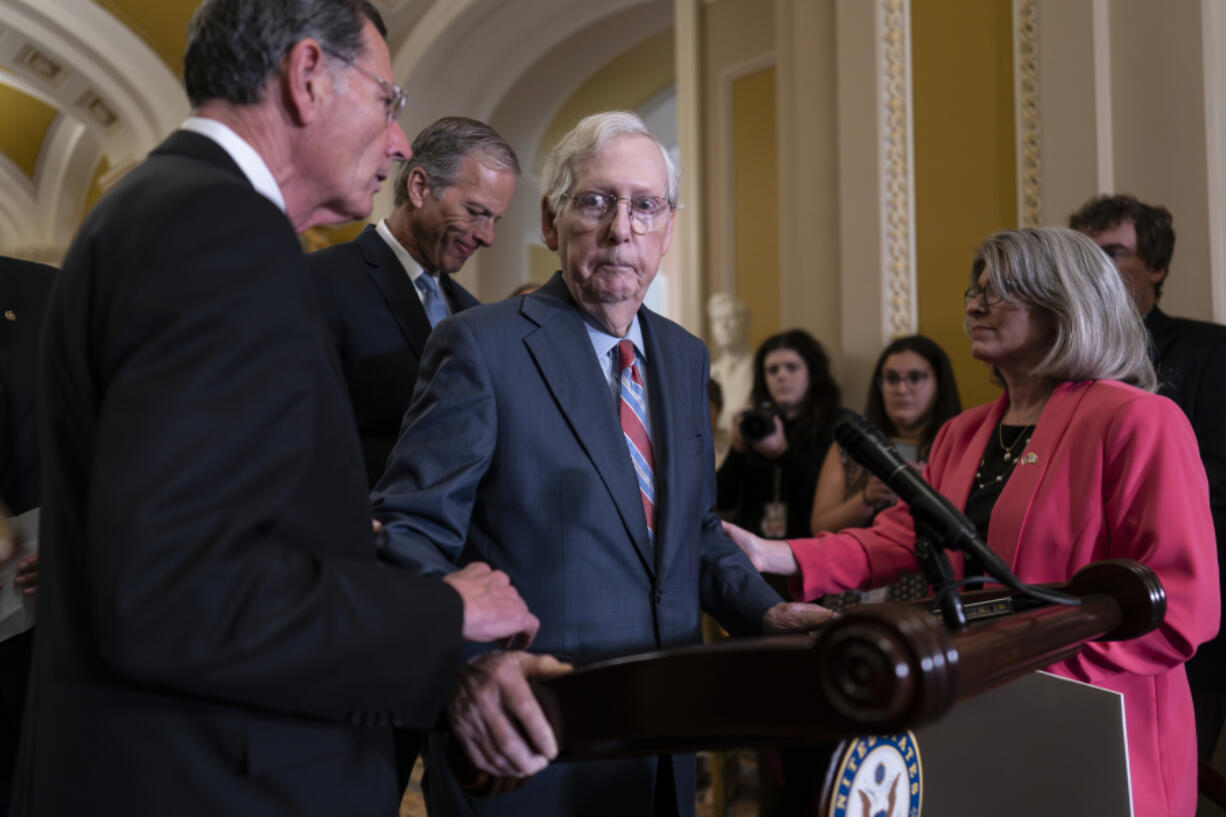 Sen. Mitch McConnell, R-Ky., center, is helped by, from left, Sen. John Barrasso, R-Wyo., Sen. John Thune, R-S.D., and Sen. Joni Ernst, R-Iowa, after the 81-year-old froze at the microphones Wednesday at the Capitol in Washington. (j.