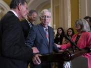 Sen. Mitch McConnell, R-Ky., center, is helped by, from left, Sen. John Barrasso, R-Wyo., Sen. John Thune, R-S.D., and Sen. Joni Ernst, R-Iowa, after the 81-year-old froze at the microphones Wednesday at the Capitol in Washington. (j.