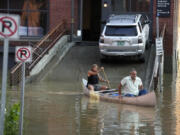 Jodi Kelly, left, practice manager at Stonecliff Veterinary Surgical Center, behind, and her husband, veterinarian Dan Kelly, use a canoe to remove surgical supplies from the flood-damaged center, Tuesday, July 11, 2023, in Montpelier, Vt. The supplies included orthopedic implants for an upcoming surgery on a dog. A storm that dumped two months of rain in two days brought more flooding across Vermont Tuesday.