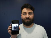 Mohammad Ahmadi poses for a portrait in Alexandria, Va., Friday, July 7, 2023, while holding a phone showing a digital photograph of his relative Nasrat Ahmad Yar who was shot and killed on July 3, in Washington, while working as a ride-share driver. Ahmad Yar was an Afghan immigrant who'd worked as an interpreter for the U.S. military in Afghanistan.