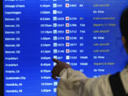 A traveler checks the departures flight board June 28 at the United Airlines terminal at Los Angeles International airport in Los Angeles.