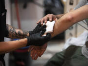 FILE - Volunteer registered nurse Jennifer D'Angelo treats Patrick C.'s skin wounds in a screened off section of the Savage Sisters' community outreach storefront in the Kensington neighborhood of Philadelphia, May 24, 2023. Xylazine, a powerful animal sedative that's moving through the illicit drug supply is complicating the U.S. response to the opioid crisis, causing gruesome skin wounds and scrambling longstanding methods for treating addiction and reversing overdoses. Federal officials are calling for more testing and research on xylazine, the powerful animal sedative that's spreading through the nation's illicit drug supply.