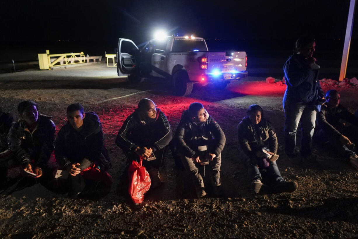 FILE - Migrants wait to be processed after crossing the border, Jan. 6, 2023, near Yuma, Ariz. A judge will hear arguments Wednesday, July 19, in a lawsuit opposing an asylum rule that has become a key part of the Biden administration's immigration policy. Critics say the rule endangers migrants trying to cross the southern border and is against the law, while the administration argues that it encourages migrants to use lawful pathways into the country and prevents chaos at the border.