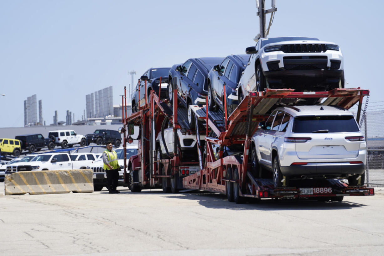 A security guard speaks with a driver of a car transport as it arrives with new cars to the former Fiat Chrysler Auto Plant now owned by Stellantis, where they will wait for future transportation Monday, July 10, 2023, in Belvidere. Ill.