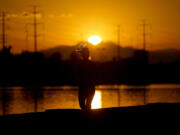 FILE - A runner jogs along Tempe Town Lake at sunrise,  July 12, 2023 in Tempe, Ariz. President Joe Biden plans to announce new steps to address the extreme heat that has threatened millions of Americans, most recently in the Southwest.