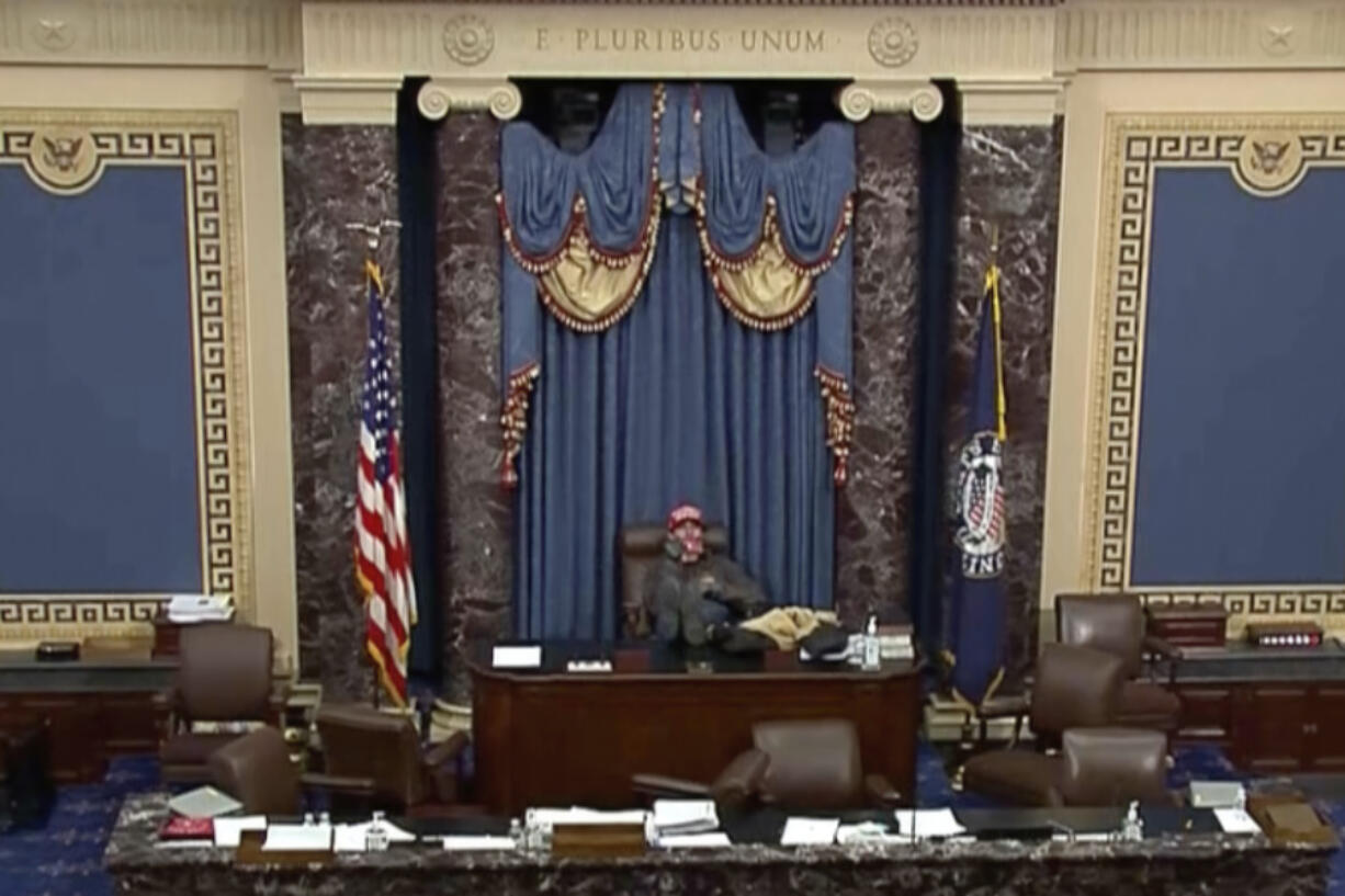 This image from U.S. Senate video, introduced at the trial of Bruno Joseph Cua, shows Cua sitting with his feet up in the Senate chamber on Jan. 6, 2021, during the riot at the U.S. Capitol.