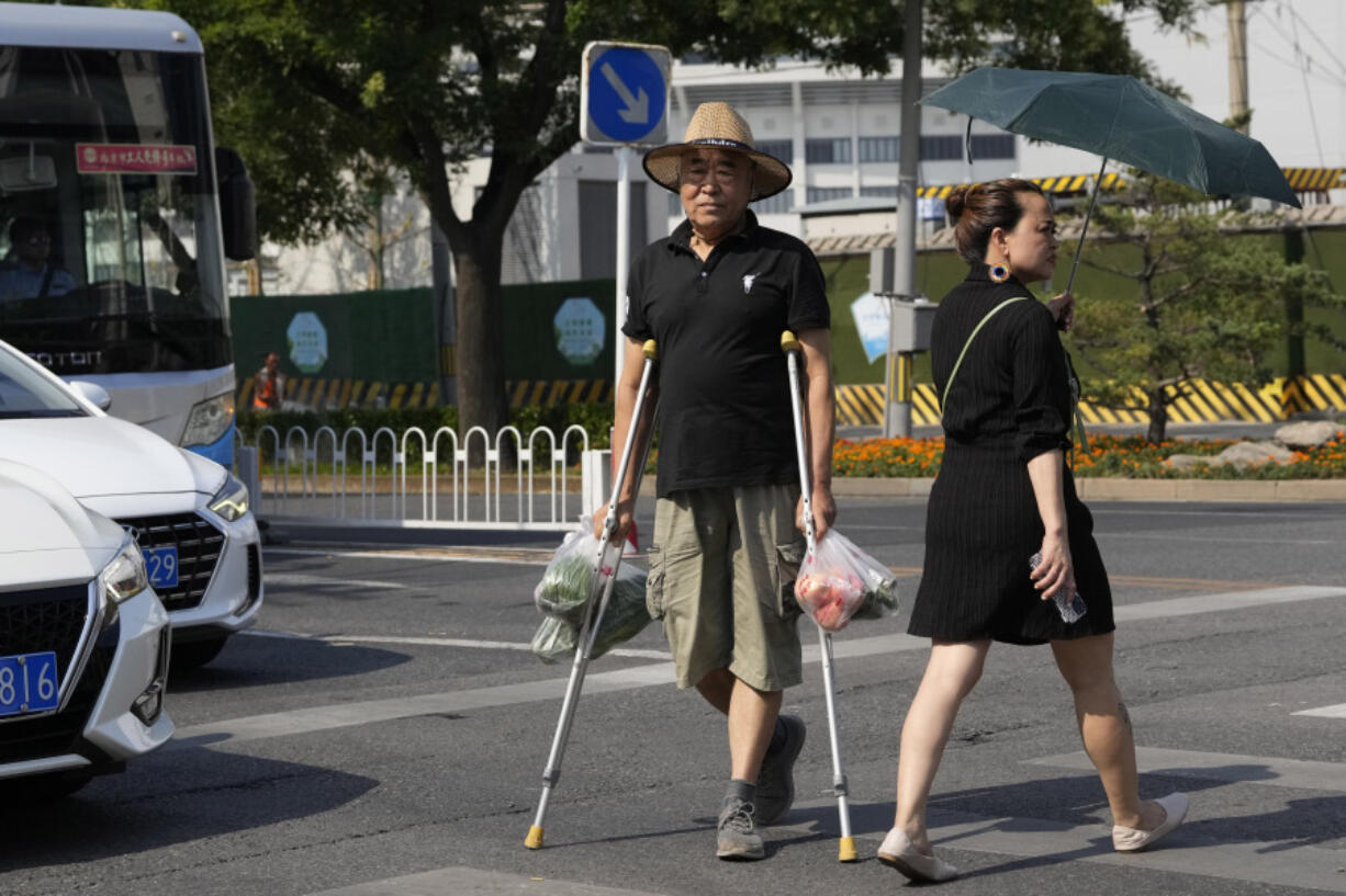 A man on crutches crosses the road with his groceries in Beijing, Monday, July 17, 2023. China's economy grew at a 6.3% annual pace in the April-June quarter, much lower than analysts had forecast given the slow pace of growth the year before.