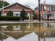 Pedestrians pass along Main Street that was damaged by flooding the previous day, Monday, July 10, 2023, in Highland Falls, N.Y. Scientists have long warned that more extreme rainfall is expected in a warming world.