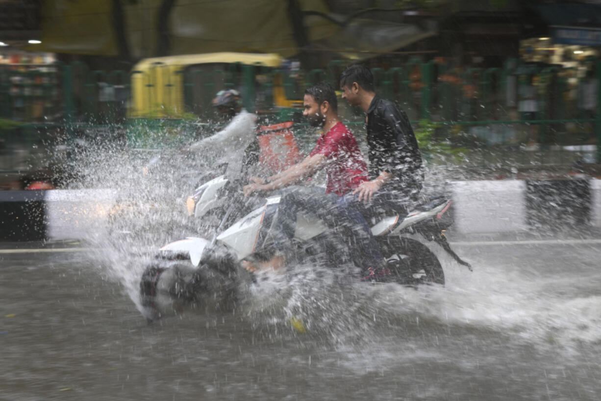 FILE - A motorcyclist drives through a water logged street during a heavy downpour in New Delhi, India, July 9, 2023. Scientists have long warned that more extreme rainfall is expected in a warming world.