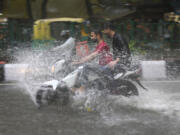 FILE - A motorcyclist drives through a water logged street during a heavy downpour in New Delhi, India, July 9, 2023. Scientists have long warned that more extreme rainfall is expected in a warming world.