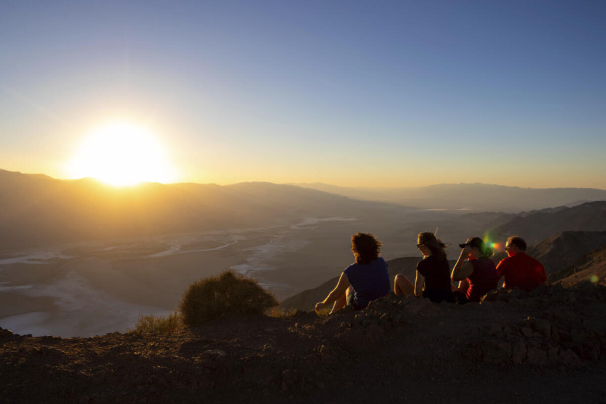 Park visitors watch the sunset on Tuesday, July 11, 2023, in Death Valley National Park, Calif. July is the hottest month at the park with an average high of 116 degrees (46.5 Celsius).