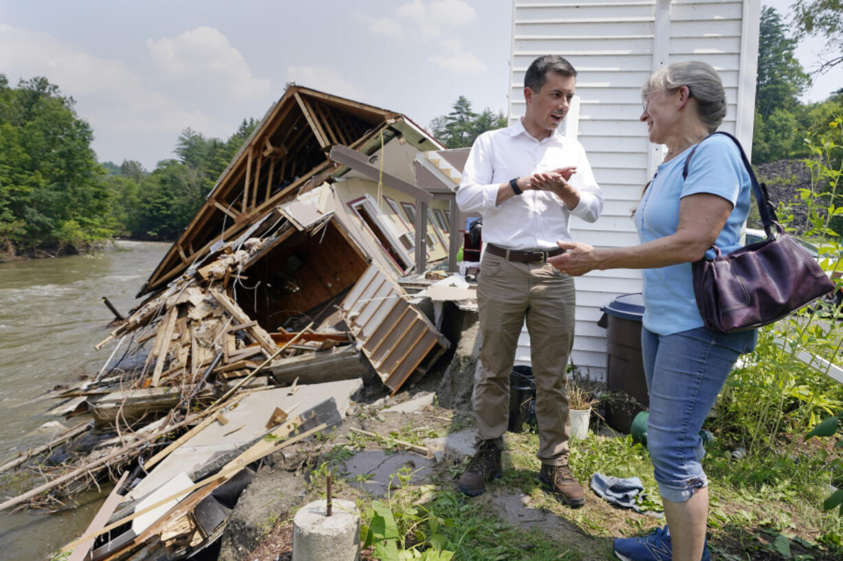 Transportation Secretary Pete Buttigieg listens to Freda Hollyer, right, owner of the Inn by the River, describe flood waters, which destroyed her family's hotel, along the banks of the Lamoille River, Monday, July 17, 2023, in Hardwick, Vt. Last week's storms dumped up to two months' worth of rain in a couple of days in parts of Vermont and New York.