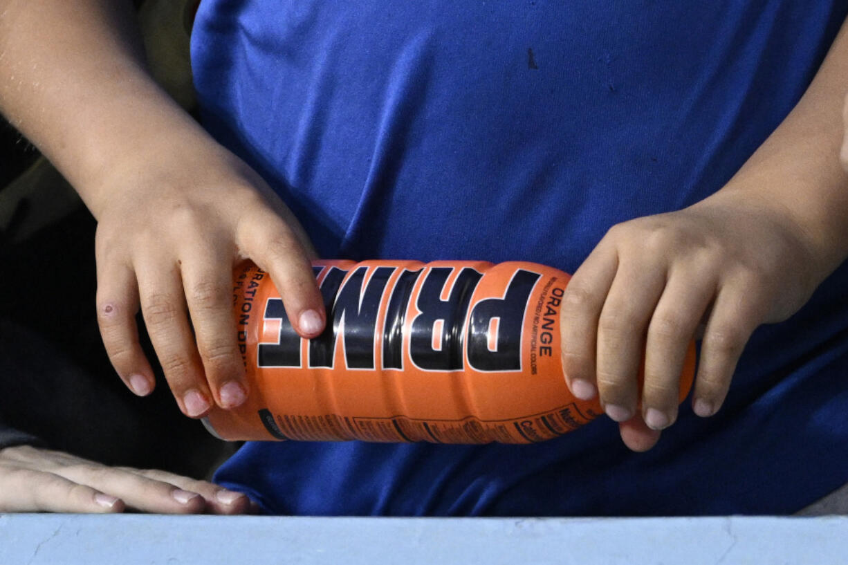 FILE - A child holds a PRIME hydration drink prior to a baseball game between the Los Angeles Dodgers and the Arizona Diamondbacks, March 31, 2023, in Los Angeles. An influencer-backed energy drink that has earned viral popularity among children is facing scrutiny from federal lawmakers and health experts over its potentially dangerous levels of caffeine. Senator Chuck Schumer on Sunday, July 9, 2023 called on the Food and Drug Administration to investigate Prime. (AP Photo/Mark J.