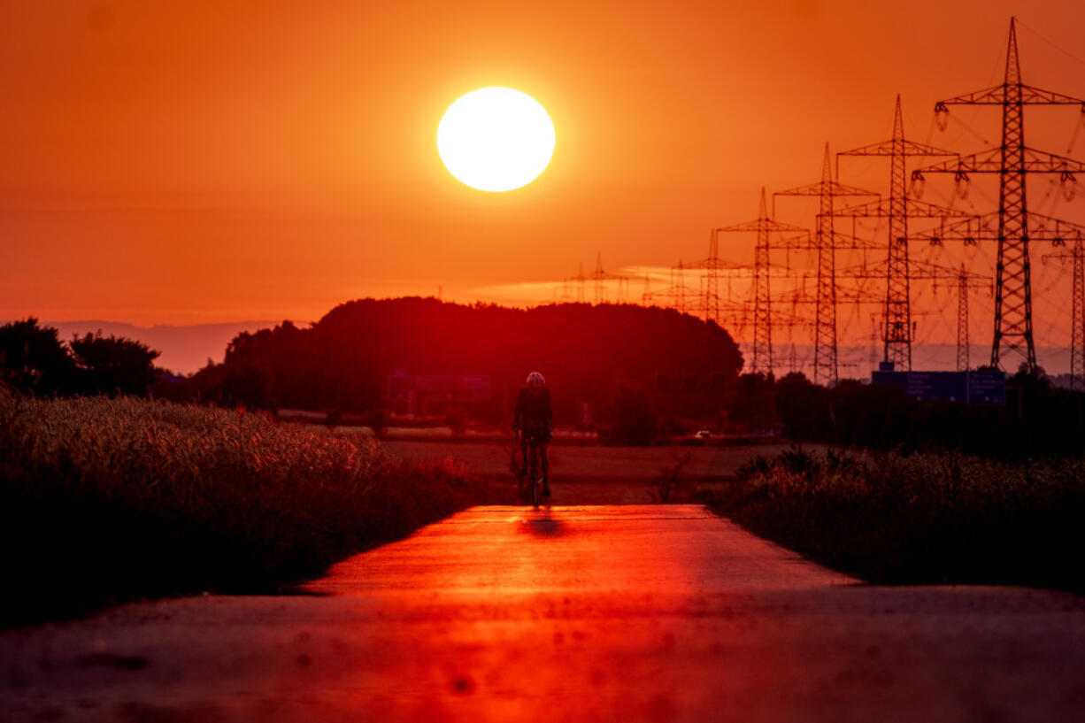 A man rides his bike on a small road in the outskirts of Frankfurt, Germany, as the sun rises on Sunday.