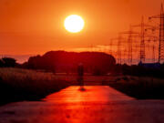 A man rides his bike on a small road in the outskirts of Frankfurt, Germany, as the sun rises on Sunday.