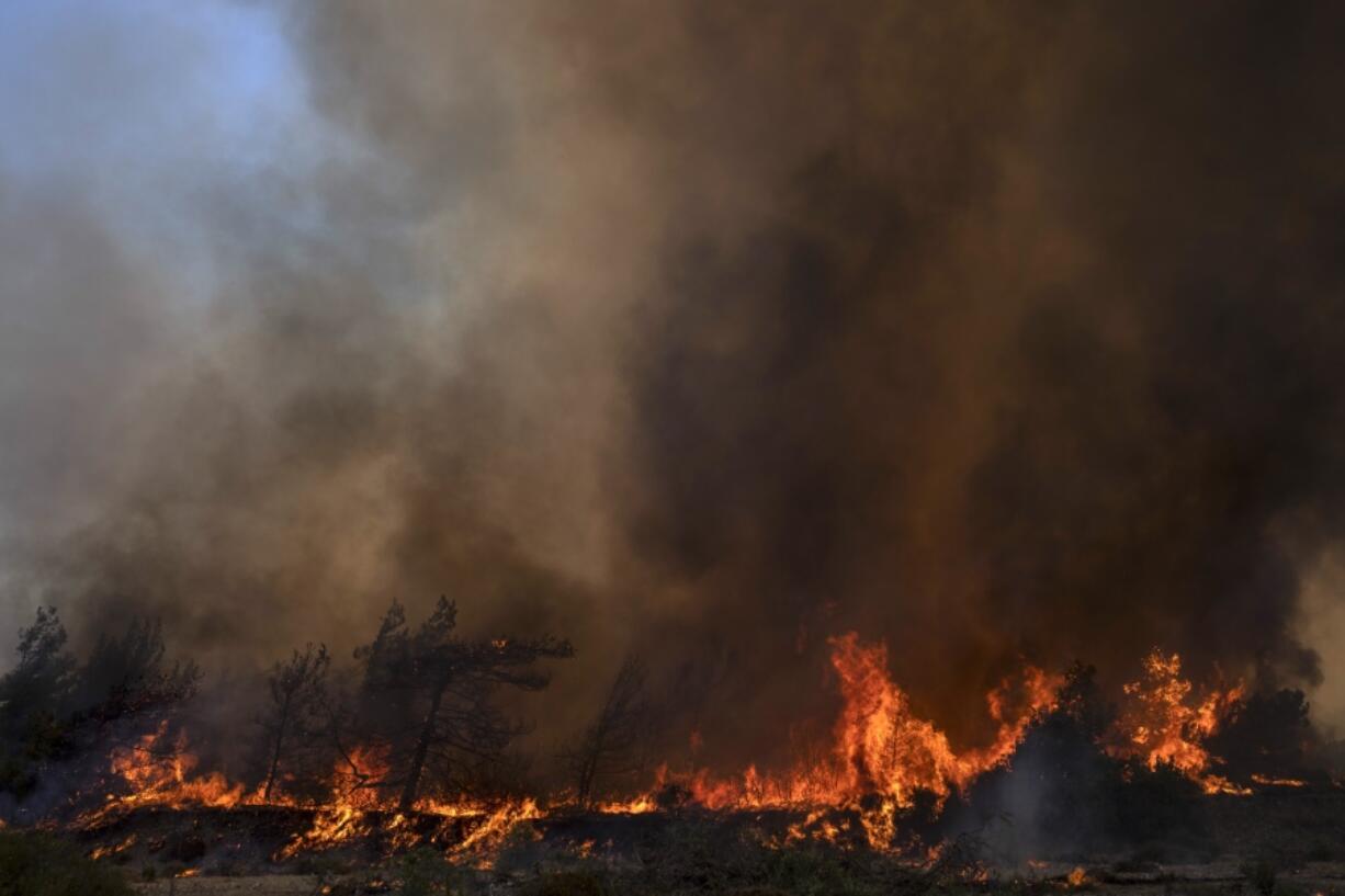 Flames burn a forest during a wildfire in Vati village, on the Aegean Sea island of Rhodes, southeastern Greece, on Tuesday, July 25, 2023. A third successive heat wave in Greece pushed temperatures back above 40 degrees Celsius (104 degrees Fahrenheit) across parts of the country Tuesday following more nighttime evacuations from fires that have raged out of control for days.