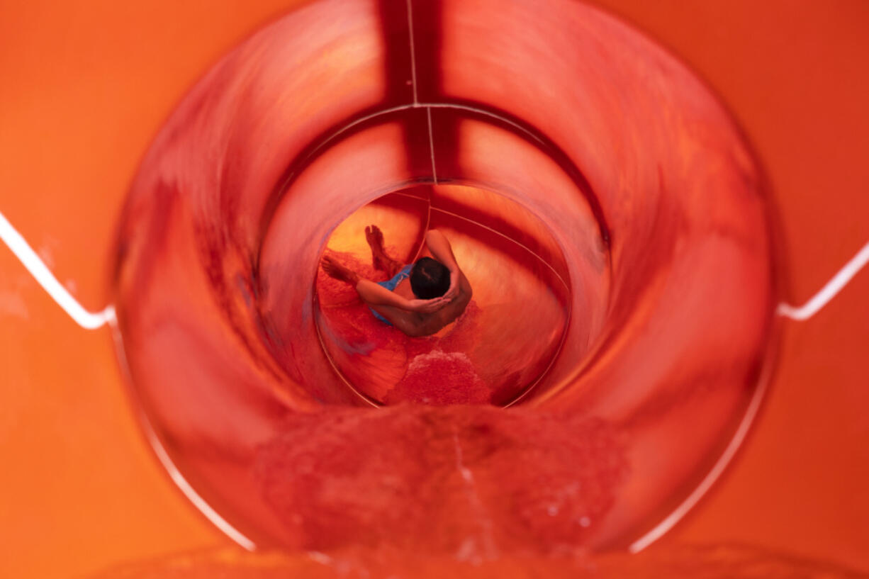 A youth enjoys a water slide at a water park of Spata town, east of Athens, Greece, Sunday, July 23, 2023. Heat in Greece is expected to grow worse during the weekend, approaching 44 Celsius (111 Fahrenheit) and the country will face one more heatwave episode by the end of July.