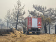 A fire-fighting vehicle makes its way through burnt trees during a forest fire, on the island of Rhodes, Greece, Sunday, July 23, 2023. Greek authorities say some 19,000 people have been evacuated from the Greek island of Rhodes as wildfires continue burning for a sixth day on three fronts.