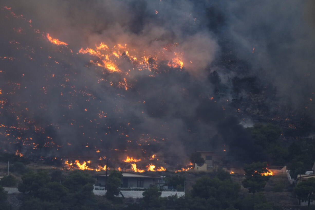 Fire approaches houses in Kalamaki near Agioi Theodori about 60 Kilometres west of Athens , on Monday, July 17, 2023. Two wildfires threatened homes in areas outside Athens, where winds of up to 70 kph made the flames difficult to contain. Most of southern Greece, including greater Athens, was an elevated level of alert for fire risk, while more extreme temperatures are expected later this week.