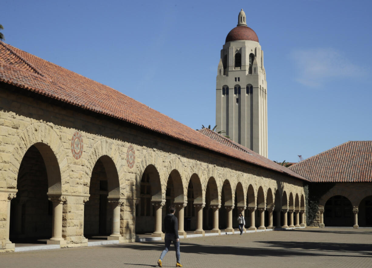 FILE - People walk on the Stanford University campus beneath Hoover Tower in Stanford, Calif., on March 14, 2019. Anonymous comments with racist, sexist and abusive messages that were posted for years on a jobs-related website for economists originated from numerous leading U.S. universities, including Harvard, Stanford, and the University of Chicago, according to research released Thursday.