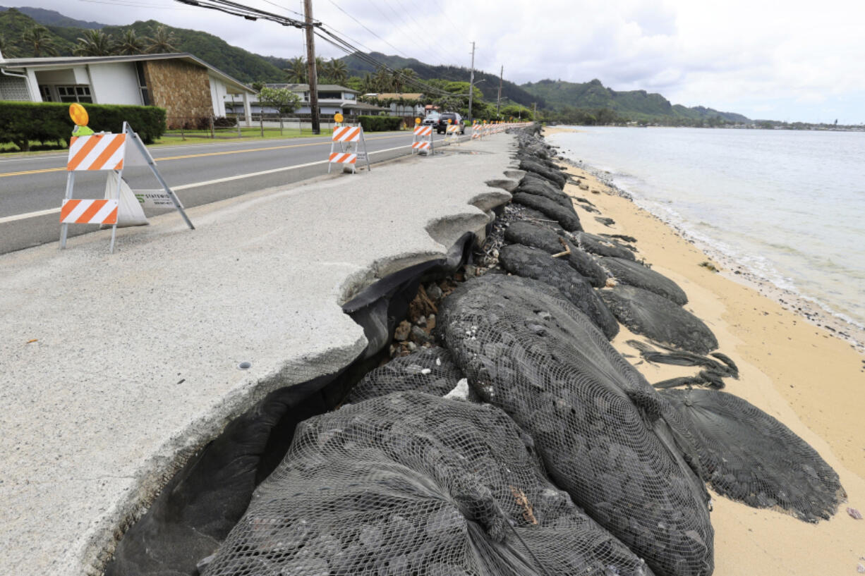Cars drive down an eroded Kamehameha Highway, Thursday, May 11, 2023, in Hauula, Hawaii. Rising seas are eroding Hawaii's coast near homes with cesspools, pulling sewage out to sea.