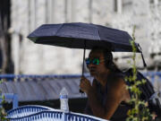 A man uses an umbrella to avoid the midday sun, Tuesday, July 11, 2023, in Los Angeles. Southern California is expecting high temperatures between 100 to 110 degrees Fahrenheit later this week according to the National Weather Service.