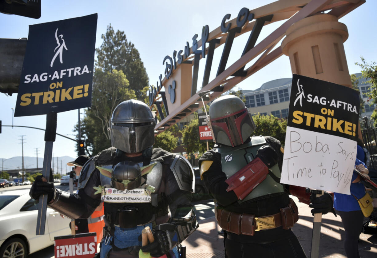 Tim Brehmer, left, and a fellow picketer dress as characters from "The Mandalorian" outside Disney studios on Thursday, July 20, 2023, in Burbank, Calif. The actors strike comes more than two months after screenwriters began striking in their bid to get better pay and working conditions.