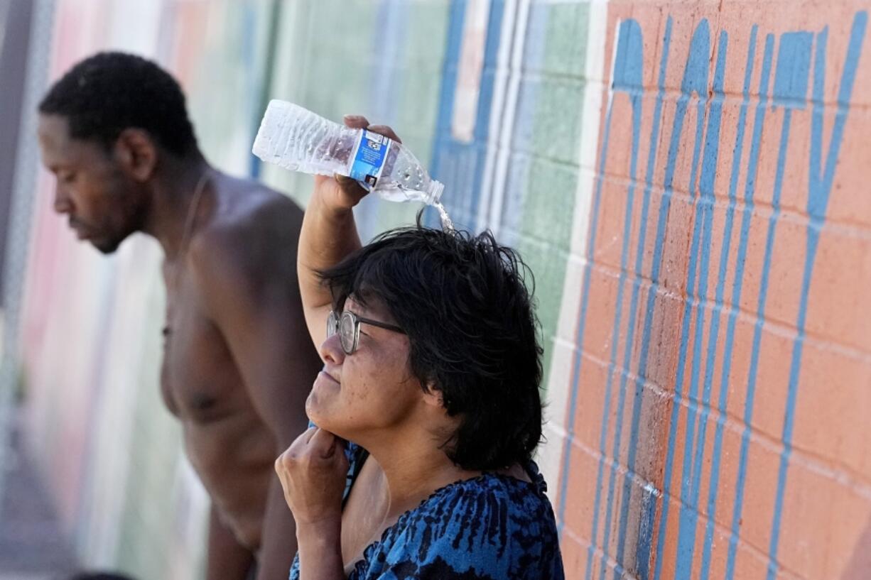 FILE - People, who are homeless, try to cool down with chilled water outside the Justa Center, a day center for homeless people 55 years and older, July 14, 2023, in downtown Phoenix. Homeless people are among the people most likely to die in the extreme heat in Phoenix.