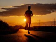 A man runs along a small road on the outskirts of Frankfurt, Germany, as the sun rises early Thursday, July 13, 2023.