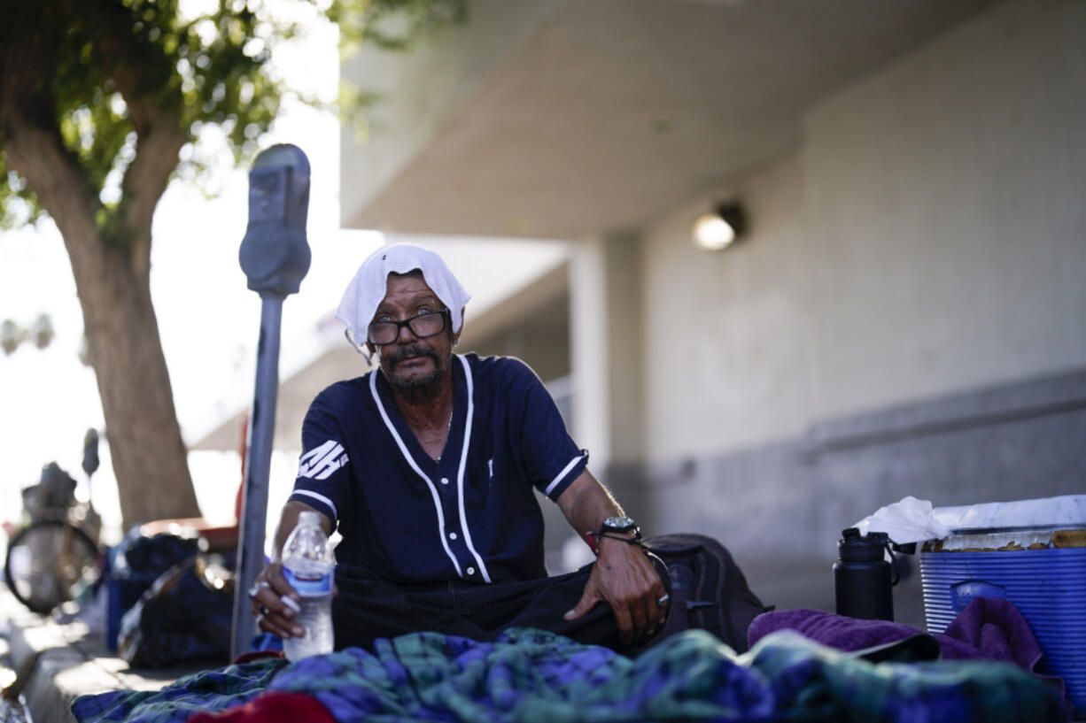 FILE - A man, who is homeless, drinks water as he wears a wet towel on his head, given to him by Maribel Padilla of the Brown Bag Coalition, July 20, 2023, in Calexico, Calif. Once temperatures hit 113 degrees Fahrenheit (45 Celsius), Padilla and the Brown Bag Coalition meet up with people who are homeless in Calexico, providing them with a cold, wet towel, and some refreshments to help them endure the scorching temperatures.