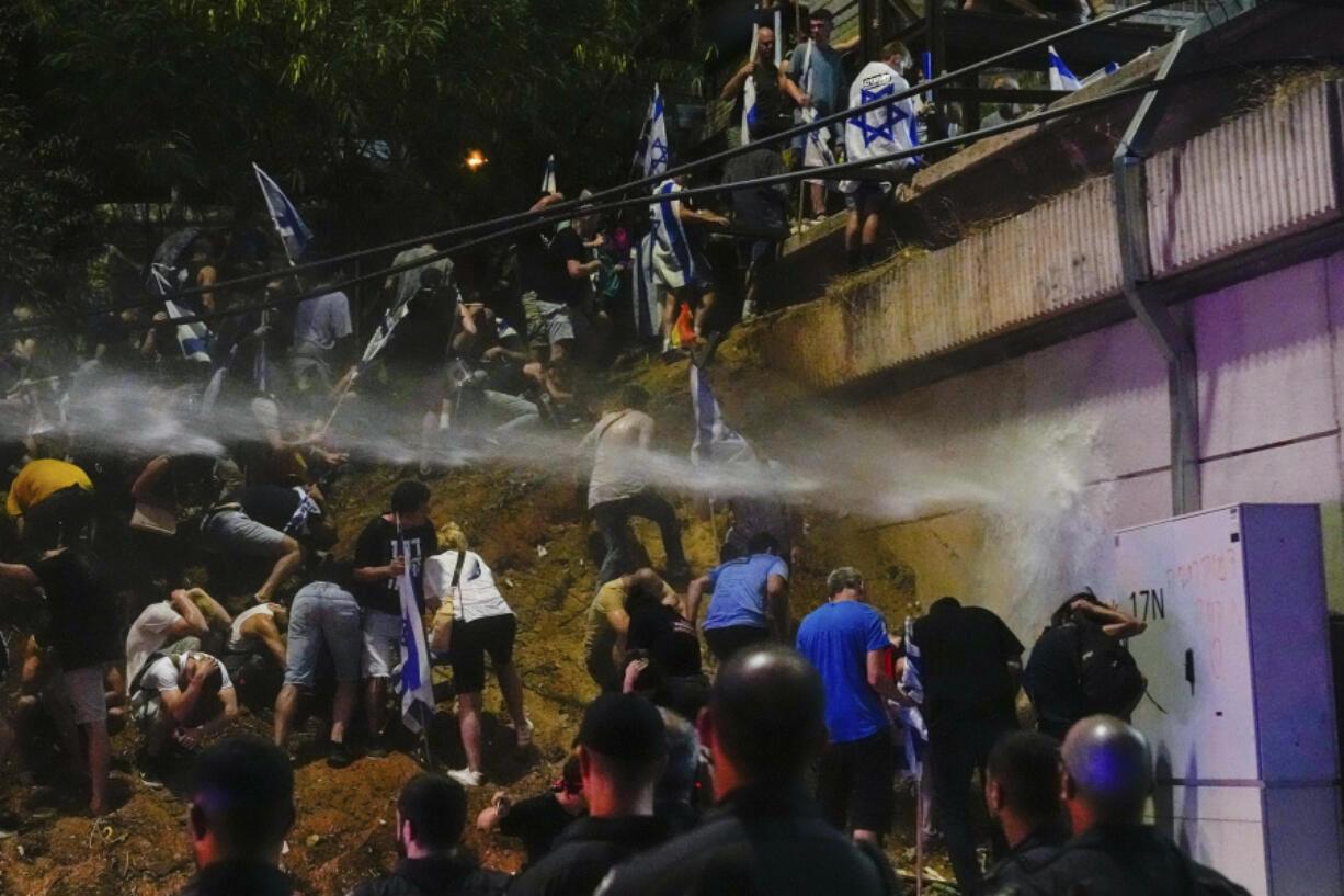 Israeli police use a water cannon to disperse demonstrators blocking the freeway during a protest against plans by Prime Minister Benjamin Netanyahu's government to overhaul the judicial system in Tel Aviv, Israel, Saturday, July 8, 2023.