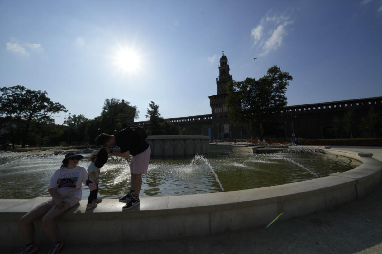 Tourists cool off in a public fountain at the Sforzesco Castle, in Milan, Italy, Saturday, July 15, 2023. Temperatures reached up to 42 degrees Celsius in some parts of the country, amid a heat wave that continues to grip southern Europe.