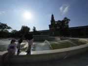 Tourists cool off in a public fountain at the Sforzesco Castle, in Milan, Italy, Saturday, July 15, 2023. Temperatures reached up to 42 degrees Celsius in some parts of the country, amid a heat wave that continues to grip southern Europe.