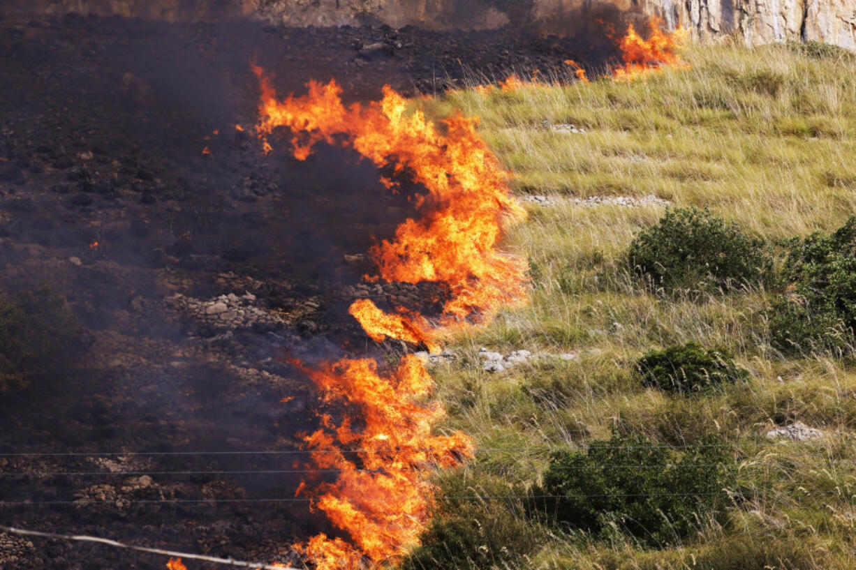 Flames burn in a field in Capaci, near Palermo, in Sicily, southern Italy, Wednesday, July 26, 2023. On the island of Sicily, two people were found dead Tuesday in a home burned by a wildfire that temporarily shut down Palermo's international airport, according to Italian news reports. Regional officials said 55 fires were active on Sicily, amid temperatures in the 40s Celsius.